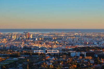 Cityscape by sea against sky during sunset