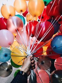 Close-up of hand holding multi colored balloons