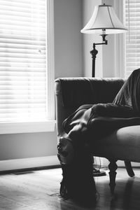 Sensuous woman wearing mask on sofa by window at home