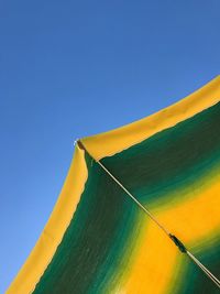 Close-up low angle view of beach umbrella against blue sky