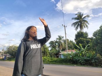 Rear view of young woman standing against sky