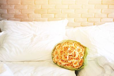 Close-up of white roses on bed against wall at home