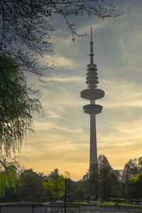 Communications tower in city against sky during sunset