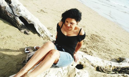 High angle view of woman sitting on drift wood