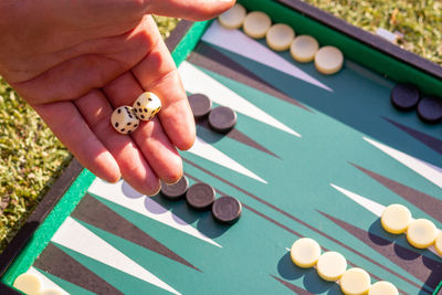 Hand holding dice over a green backgammon set