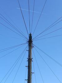 Low angle view of electricity pylon against clear blue sky
