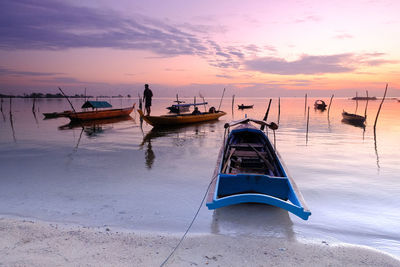 Boat moored on shore against sky during sunset