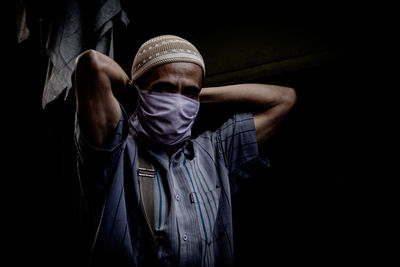 Portrait of young man standing against black background