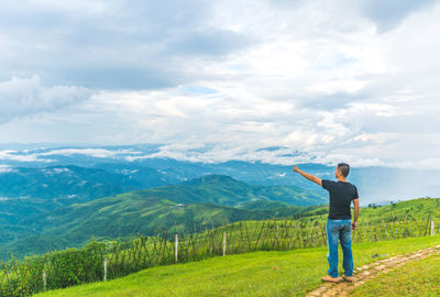Full length of man looking at green landscape against sky