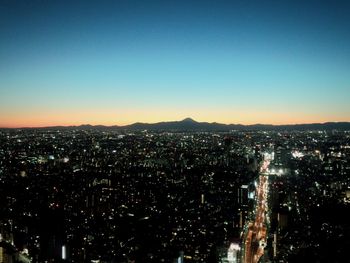Illuminated cityscape against clear sky at night