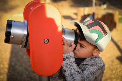 Close-up of boy looking through coin-operated binoculars