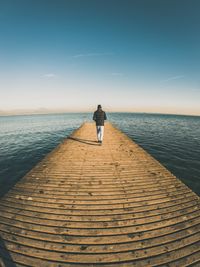 Rear view of man standing on sea against sky