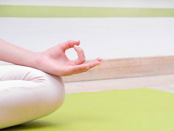 Midsection of woman doing yoga in studio