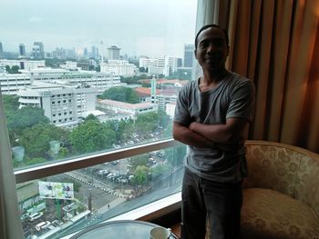 Young man looking at cityscape through window