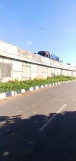 Road by building against clear blue sky