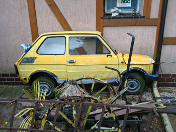 Old yellow car parked by building