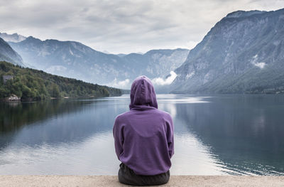 Rear view of woman looking at lake against mountains