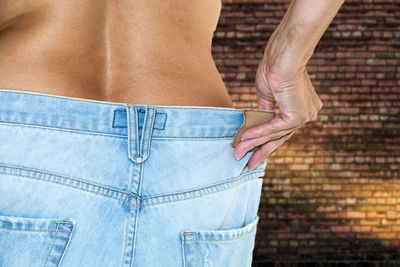 Midsection of woman wearing jeans at home