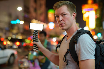 Full length portrait of man photographing illuminated city