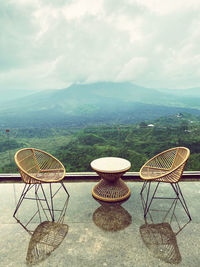 Empty chairs and tables against sky