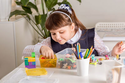 A girl pupil disassembles a box with small toys 