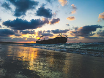 Scenic view of sea against sky during sunset with a shipwreck in sight