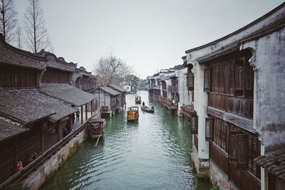 Canal amidst houses against clear sky