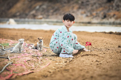 Full length of boy with puppies on land