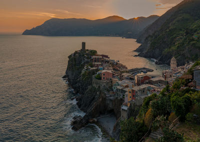 Scenic view of beach by town against sky during sunset