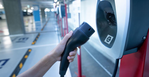 Hand holding electric charger at an electric vehicle charging station. commercial ev car charging