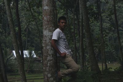 Portrait of young man on tree trunk in forest