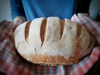 Homemade rye bread with sourdough is held in the hands and in a towel