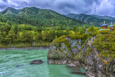 Scenic view of river by mountains against sky