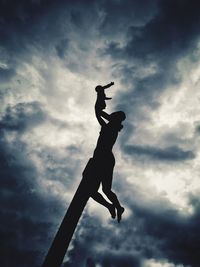 Low angle view of silhouette woman jumping against sky