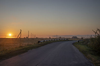 Road by street against sky during sunset