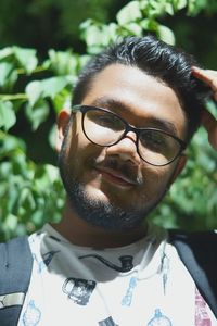 Close-up portrait of young man wearing eyeglasses against plant