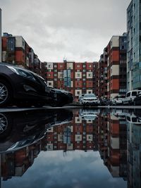 Reflection of buildings in canal against sky in city
