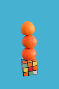 Stack of orange fruits on toy block over blue background