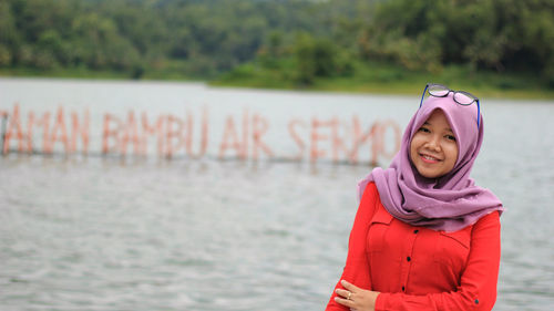 Portrait of a smiling young woman by lake