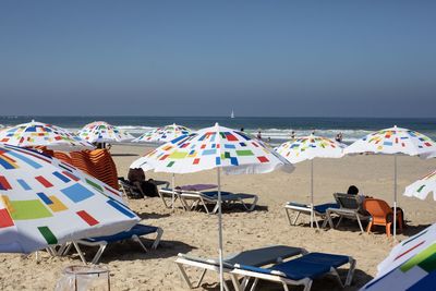 Deck chairs and parasols on beach against sky