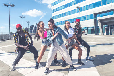 Friends dancing against building in city