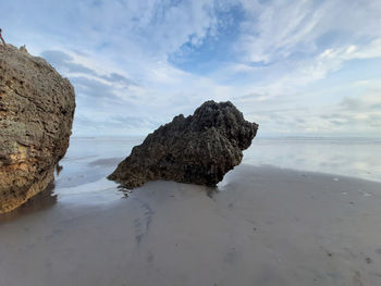 Rock formations on shore against sky