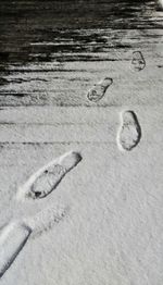 Close-up of footprints on sand at beach during winter