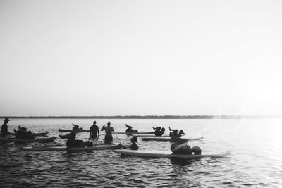 People in sea against clear sky