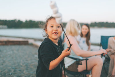 Portrait of happy girl sitting by lake