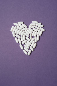 High angle view of heart shape pills on purple background