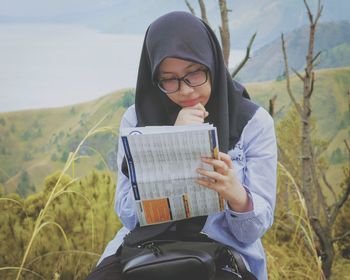 Young woman reading papers on mountain