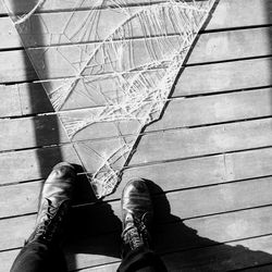 Low section of person standing by broken glass on footpath