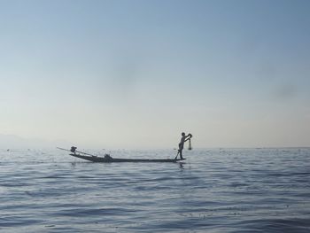 Man fishing in sea against sky