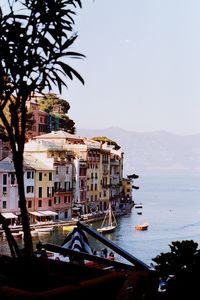 Buildings by sea against clear sky